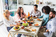 © Alessandro Grandini - Group of multiethnic friends sitting at the table during lunch