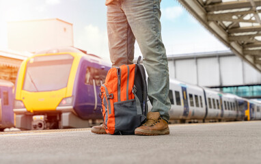 Traveler with a suitcase and  suit waiting for a train at the train station.   Travel concept.