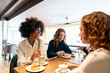 © Westend61 - Happy woman spending time with friends in cafe