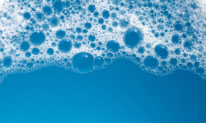 Wall Mural - Detergent foam bubble on water. Blue background, Soap sud