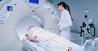 © ihorvsn - Female medical worker dressed up in gown before MRI procedure. Female doctor is gesturing and preparing patient for magnetic resonance procedure. Patient is lying at CT bed and listening to doctor.