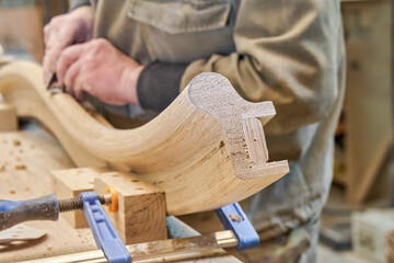 Wall Mural - Carpenter sands bending wooden railing with sandpaper in workshop closeup. Senior master makes detail of spiral staircase for home interior