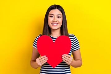 Sticker - Photo of positive adorable pretty lady wear striped stylish clothes hold show big red paper card isolated on yellow color background