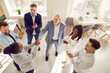 © Studio Romantic - African american women shaking hands with man celebrating success, making deal, business achievement, signing contract or greeting new employee with group of people applauding in office. Top view.