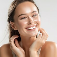 Woman smiling while touching her flawless glowy skin, skincare