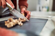 © Jelena - A man cutting mushrooms on a kitchen counter and preparing a delicious meal.