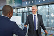 Businessmen handshaking in airport concourse