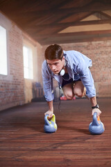 Wall Mural - Young man jumping with kettle bells in gym studio