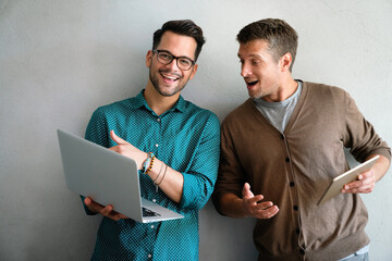 Young manager talking with experienced colleague while using computer in office.