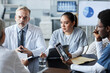 © Seventyfour - Confident mature doctor and his young female assistant looking at their colleague sitting in front of them and explaining working point