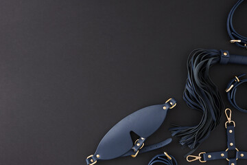 Wall Mural - Erotic enjoyment BDSM toy ideas. Top view photo of cuffs, blindfold mask, leather whip on black background with empty space for advert or text