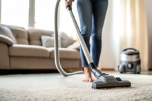 Young Woman Hoovering Carpet At Home, Closeup.