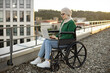 Focused young female with mobility impairment using portable computer while staying in open air on roof. Professional arabian entrepreneur in hijab analyzing new project via modern technologies.