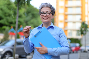 Poster - Friendly stylish woman realtor with documents and apartment keys in her hands.