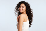 A model girl with glowing skin and thick black and curly hair looks over her shoulder at the camera against a blue background