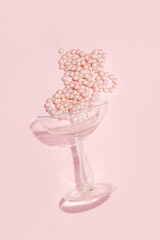 Old style champagne glass and pastel pink pearls, creative aesthetic girl's party concept.