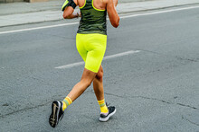 Side View Female Runner Running Marathon Race In Bright Green Tights