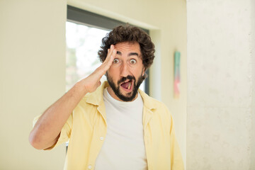 Wall Mural - young crazy bearded man looking happy, astonished and surprised, smiling and realizing amazing and incredible good news