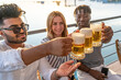 © Marino Bocelli - small group of young adult multiethnic friends toasting with three mugs of beer