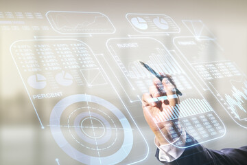 Poster - Multi exposure of businessman hand with pen working with creative statistics data hologram on blurred office background, stats and analytics concept