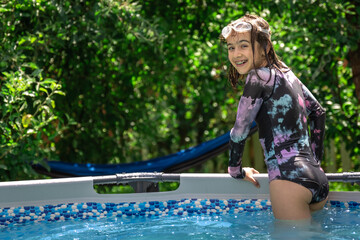 little girl playing in a swimming pool at a summer garden.