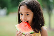 6 year old girl eating watermelon outside on hot summer day