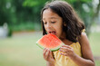 6 year old girl eating watermelon outside on hot summer day