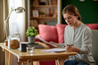 © Stockphotodirectors - Mid adult woman examining her bank statement at home office using laptop