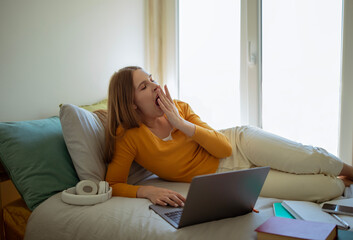 Wall Mural - Sleepy Lady Yawning Doing Homework At Laptop In Bedroom Interior