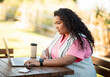 © Prostock-studio - Side view of young hispanic lady typing on laptop outdoors