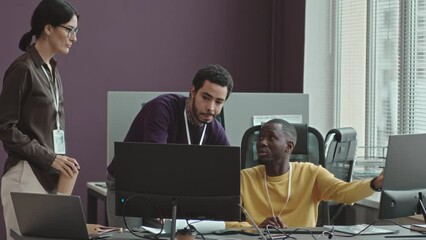 Medium shot of diverse team of young creative software developers discussing new application while coworking in office