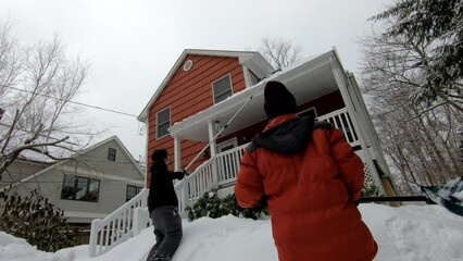 Wall Mural - young man removing snow from roof and woman shoveling the snow after the snow storm