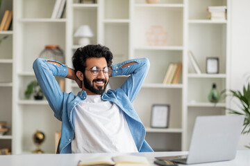 After Productive Day. Happy indian man leaning back in chair and smiling