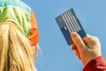 The girl holds the European Health Insurance Card in her hand, Concept, EU document confirming the right to treatment abroad, Travel insurance for Europeans traveling to EU and EFTA countries