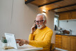 © Miljan Živković - One senior man sit work in tiny house use smart phone make a call