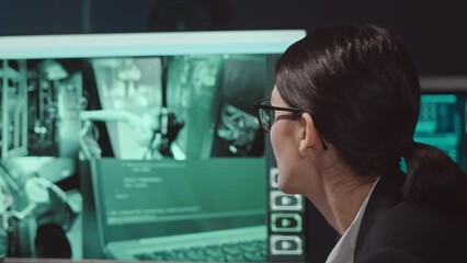 Wall Mural - chest up of female cybersecurity specialist watching her colleagues operating in server room via cct
