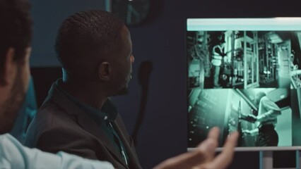 Wall Mural - chest up of two multiethnic male cybersecurity specialists having discussion while watching server r