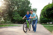 asian dad teaches son to ride bike, korean senior helps child, boy in helmet is actively relaxing with his father