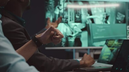 Wall Mural - diverse male cybersecurity workers watching cctv cameras in server room where their colleagues inspe
