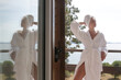 Woman in white terrycloth bathrobe on balcony.