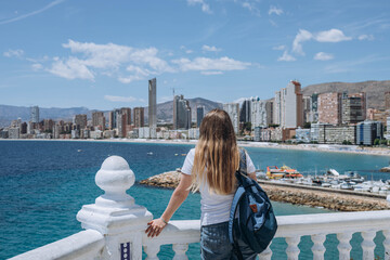 Young carefree tourist woman in white sun hat enjoying sea or ocean view in Balcon del Mediterraneo, Benidorm, Spain. Summer holiday vacation