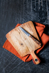 Wall Mural - wooden Cutting board with knife and napkin on stone dark backdrop Surface copy space for design text