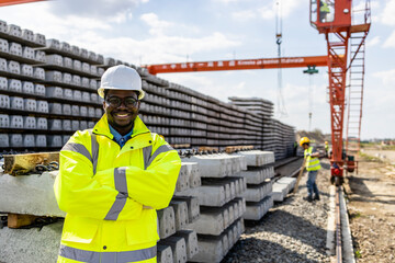 Portrait of civil engineer holding arms crossed at road and railroad construction site.