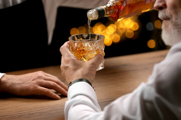 Poster - Bartender pouring whiskey in glass for customer at bar counter, closeup