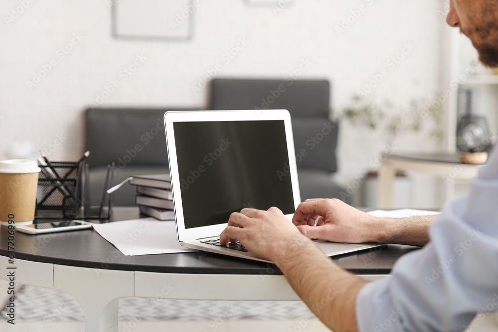 Young businessman working with laptop at table in office, closeup