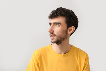 Young brunette man with stylish hairdo on light background, closeup