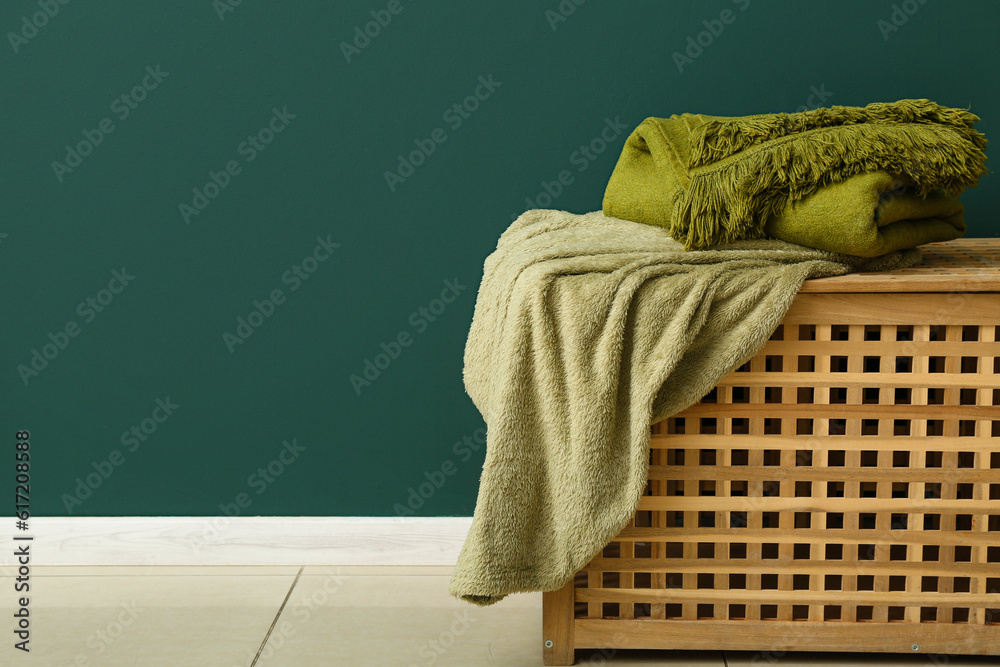 New soft blankets on basket near green wall