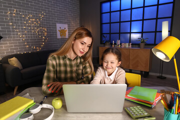 Wall Mural - Little girl with her mother doing lessons at home late in evening