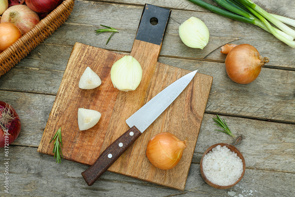 Board with different kinds of onion on brown wooden background