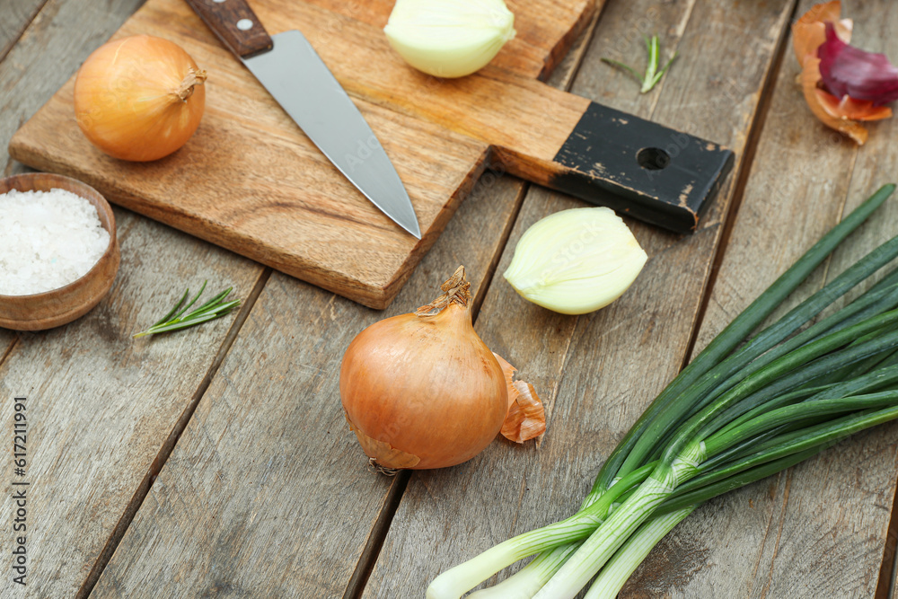 Board with different kinds of onion on brown wooden background
